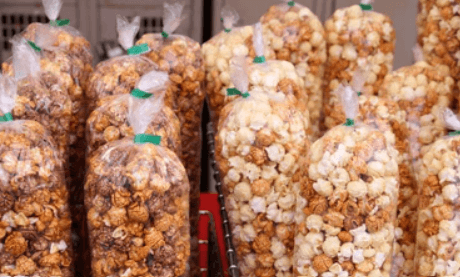 Rows of clear bags containing caramel-coated and plain popcorn, secured with green twist ties.